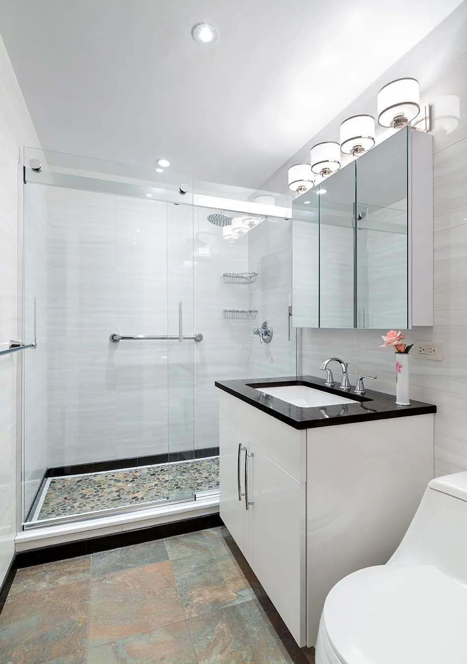 A bright NYC bathroom with a curbless, frameless glass walk-in shower