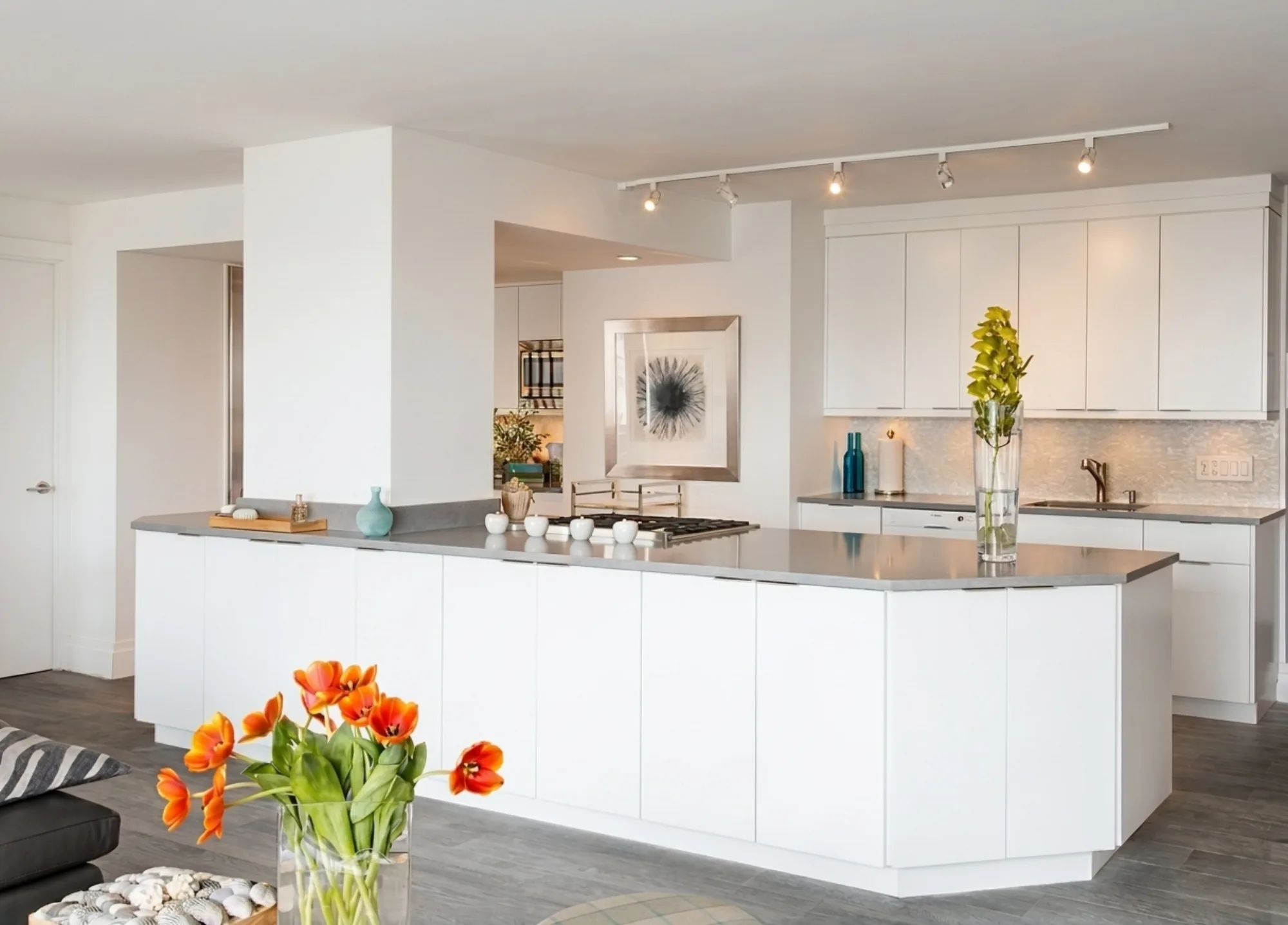 A sleek handleless white NYC kitchen with a gray quartz waterfall island