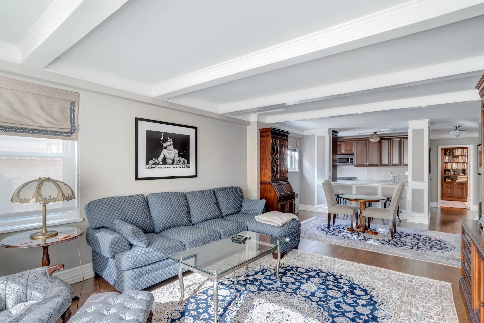 A restored prewar living room with a beamed ceiling and crown moldings