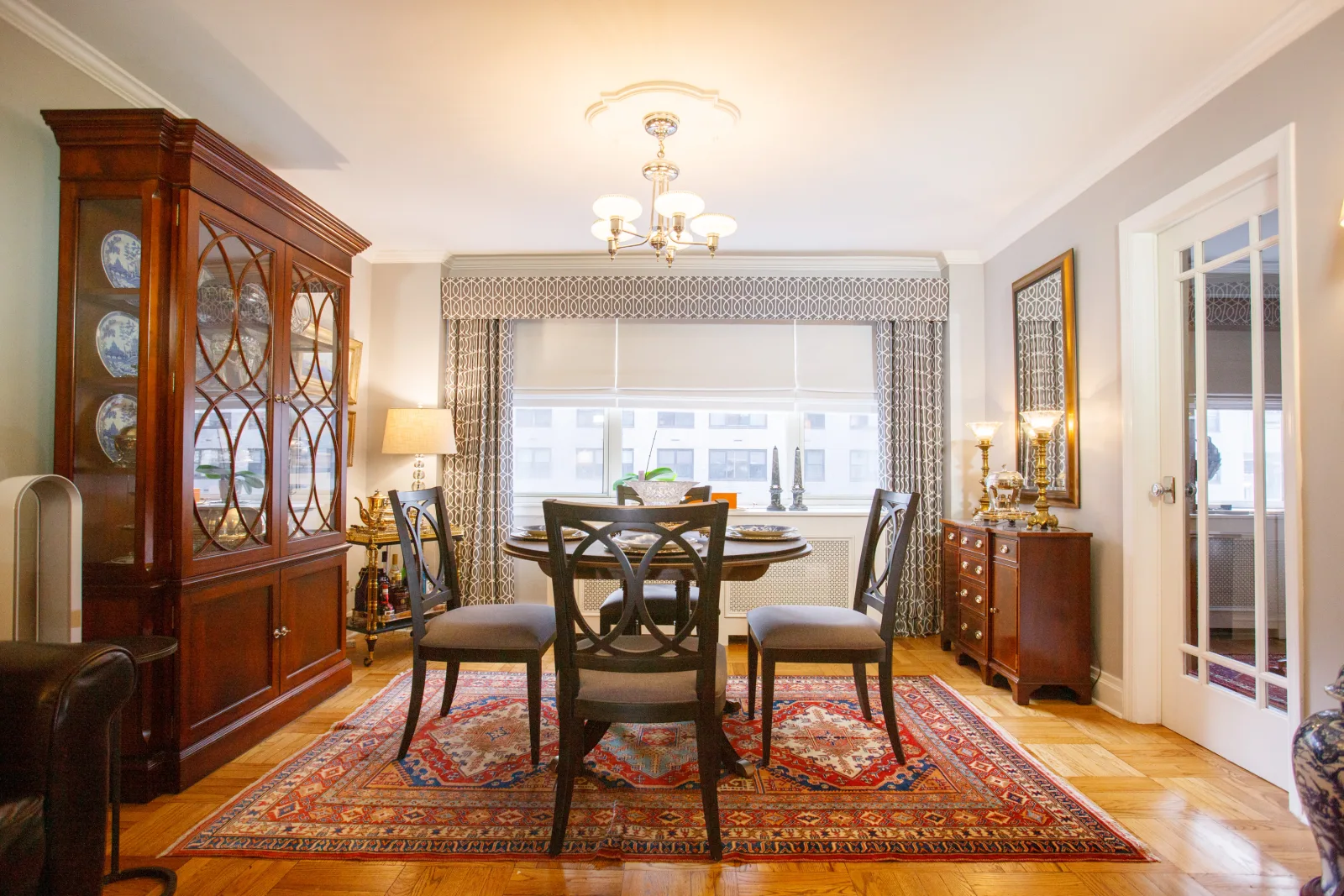 A prewar NYC dining room with restored oak parquet floors, a china cabinet, and a chandelier