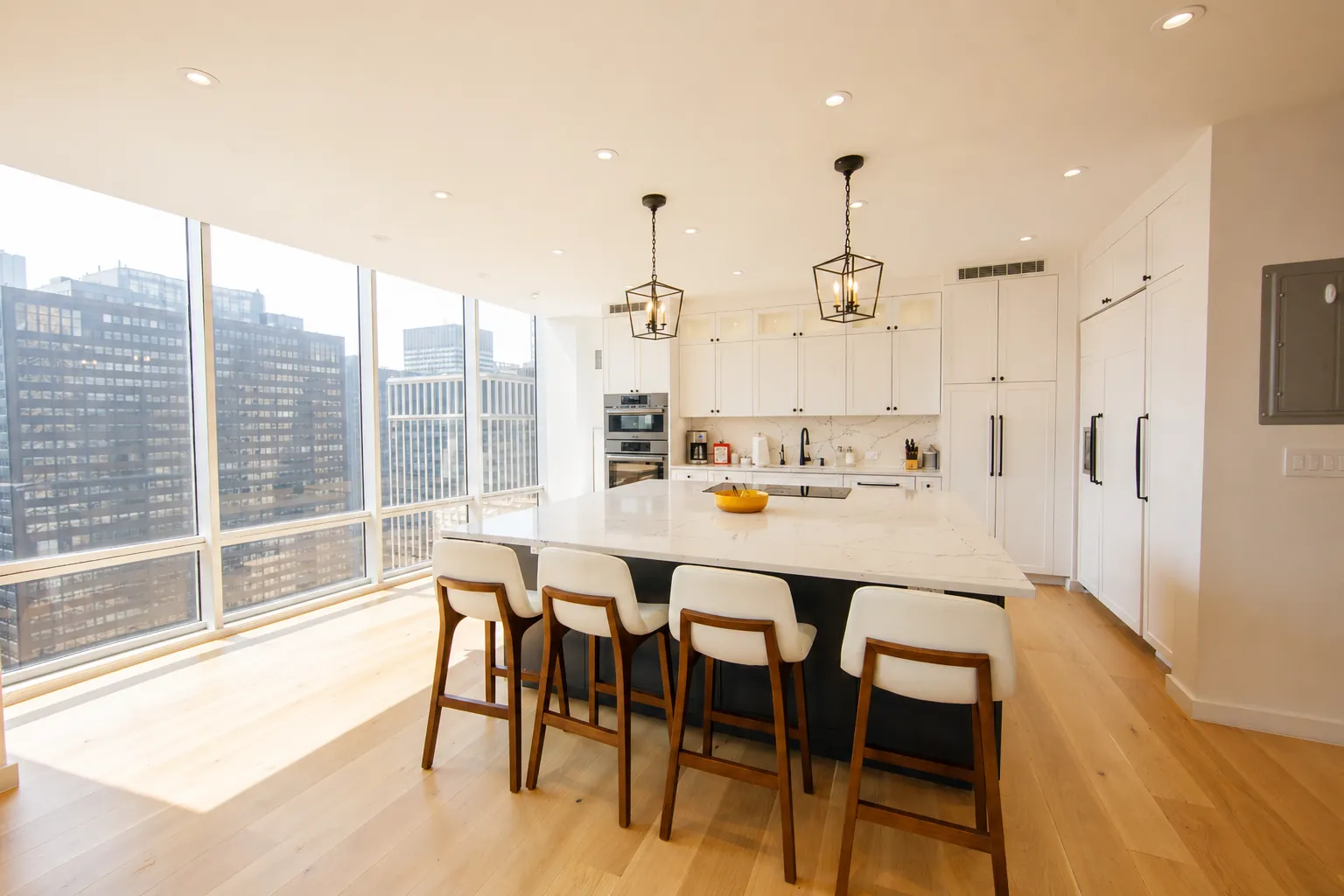 A marble waterfall island in an open NYC kitchen with floor-to-ceiling skyline views