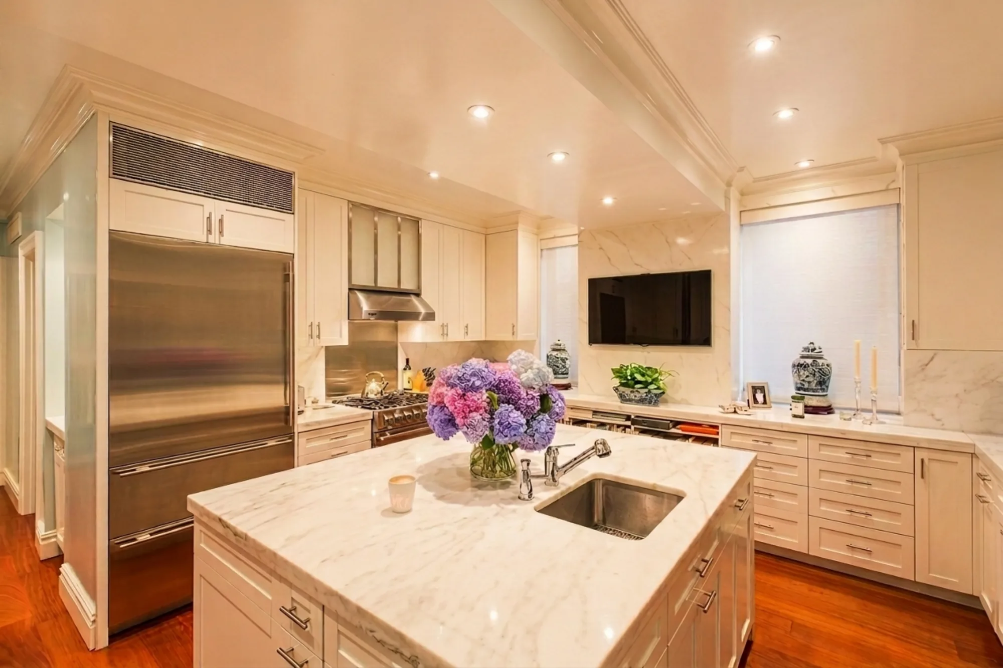 A cream Shaker NYC kitchen with a marble island and a Sub-Zero refrigerator