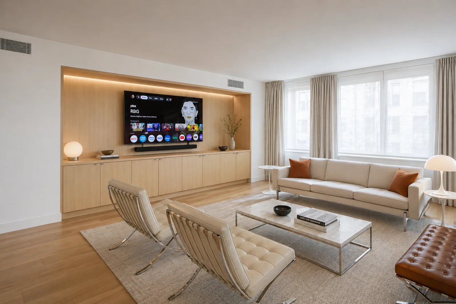 A minimalist renovated NYC living room with a white oak built-in media wall backlit by an LED cove and city windows
