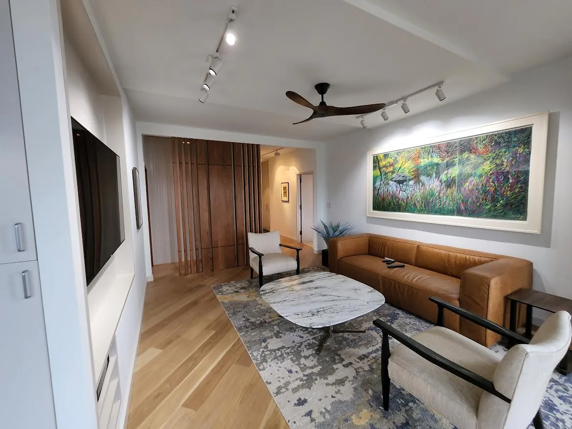 A bright, open NYC living room with wide circulation, a built-in media wall, and layered lighting