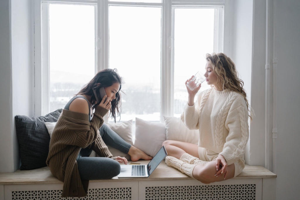 Two girls sitting on a window seat.