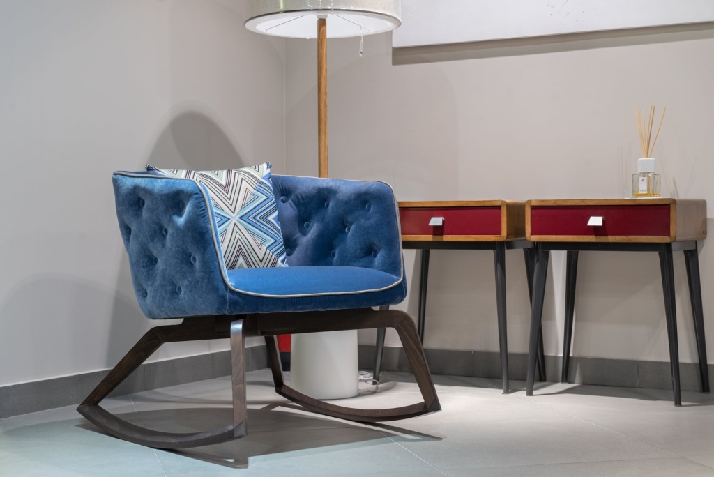 A blue chair next to decorative tables. 