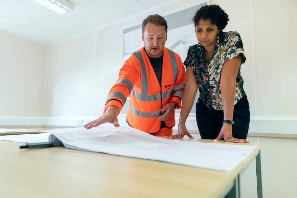 A man in an orange safety vest explaining a plan 